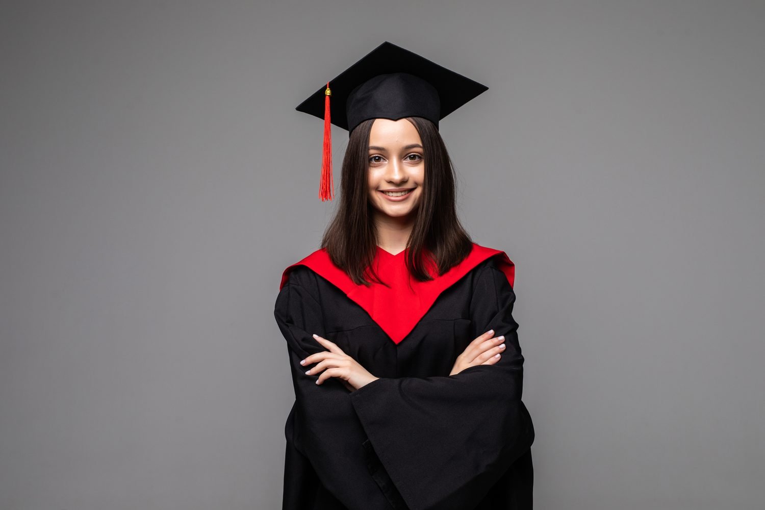 Graduada con toga negra y estola roja, sonriendo con los brazos cruzados