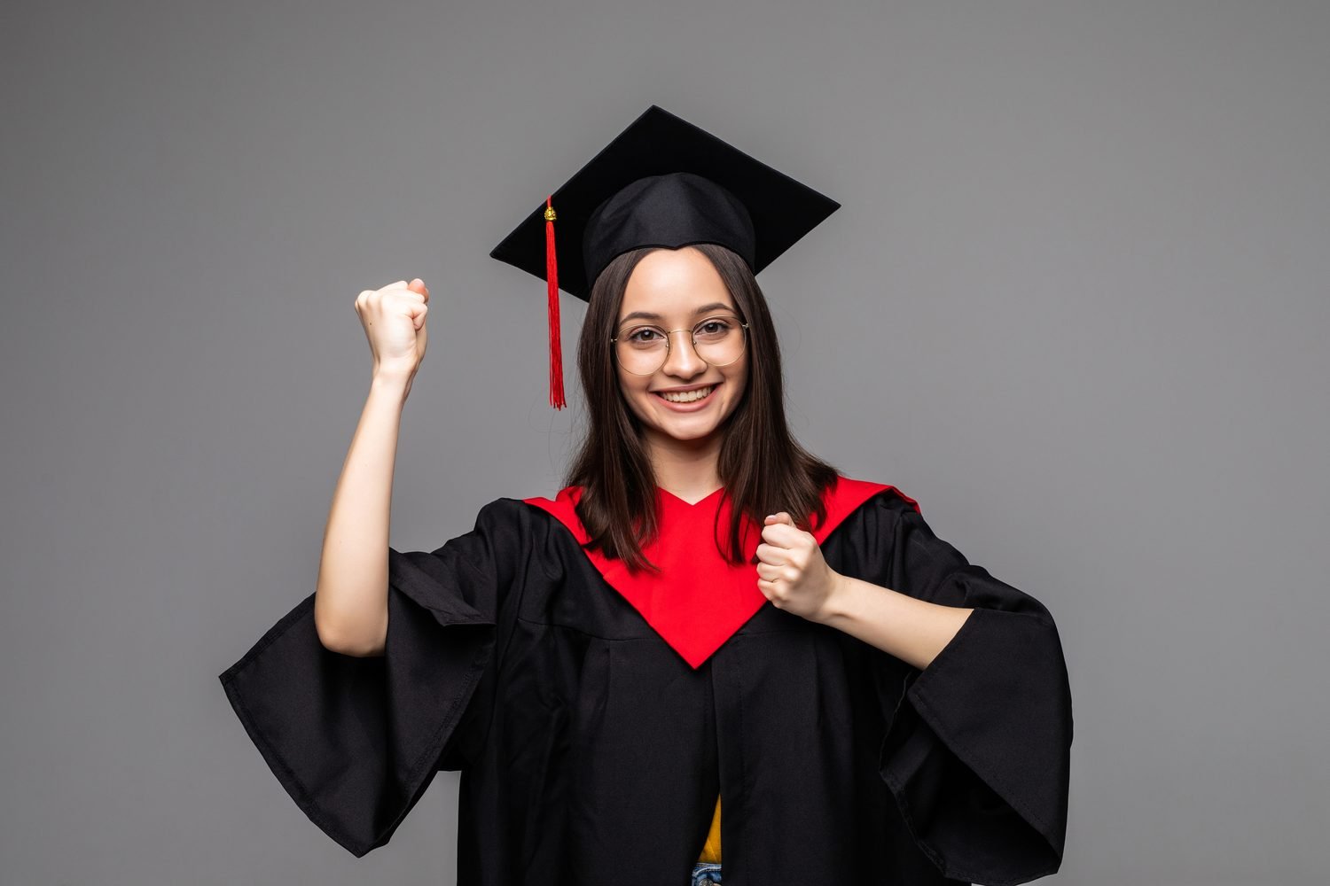 Graduada con lentes celebrando con los puños en alto
